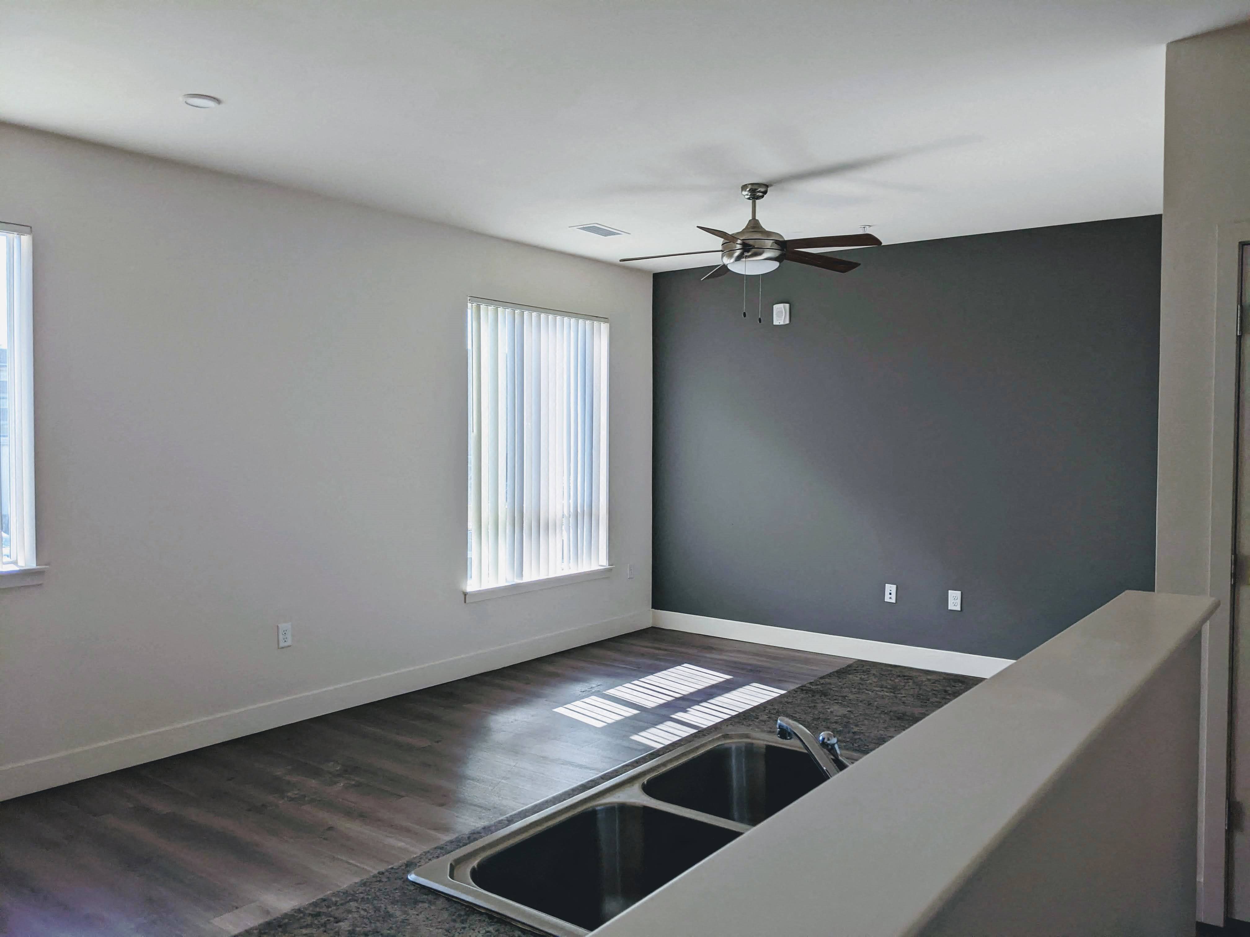 A living room with a window, ceiling fan